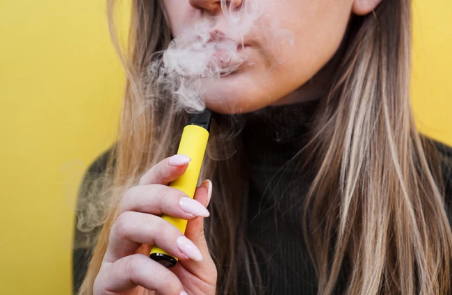 Woman-vaping-a-disposable-vape-device